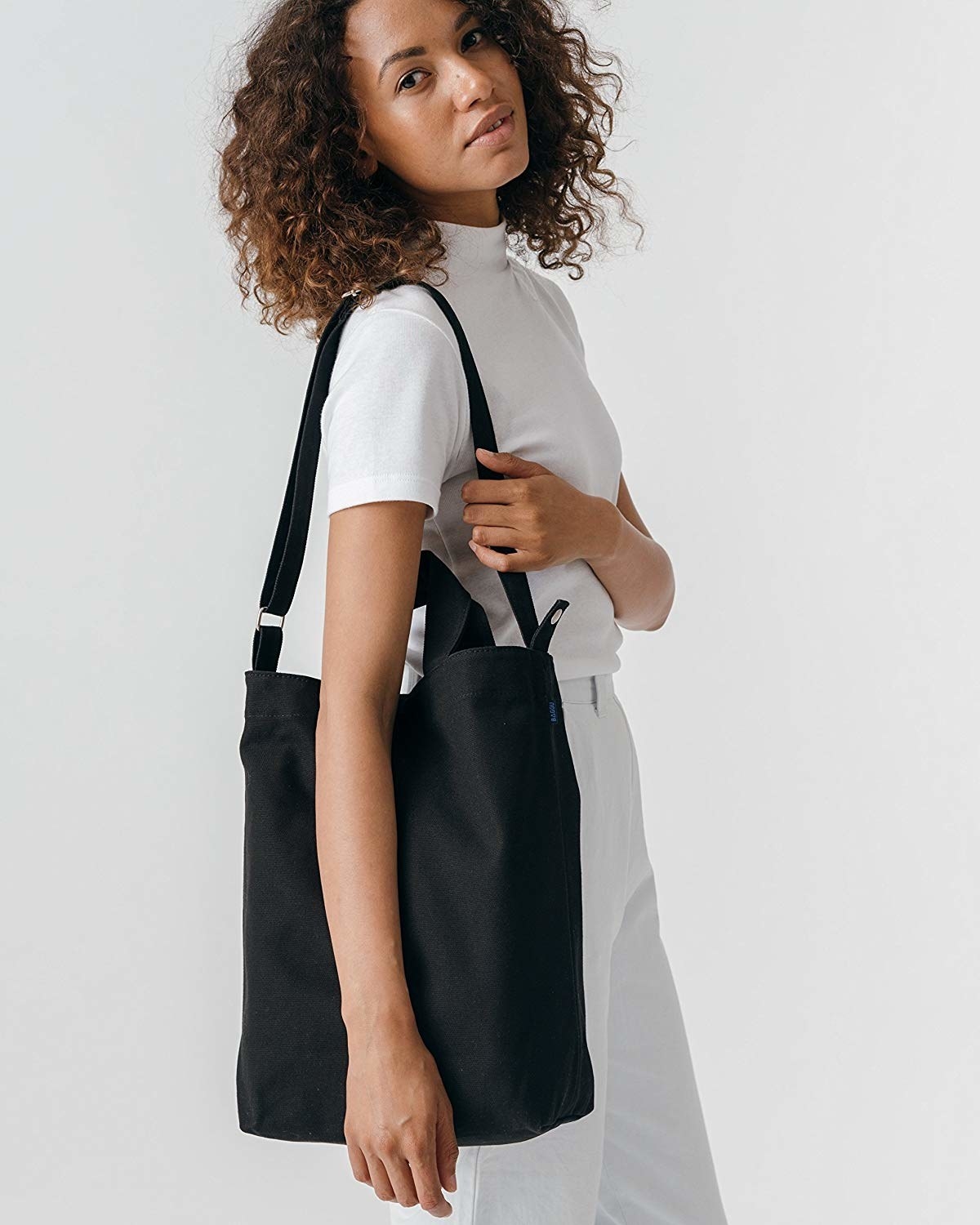 model wearing the tote bag over their shoulder that also has short handles in black