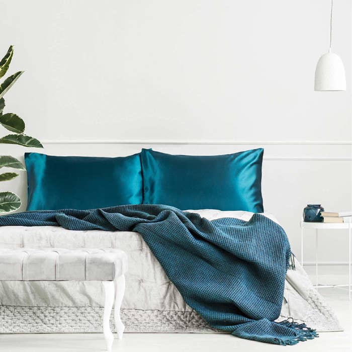 Two teal satin pillowcases on a bed