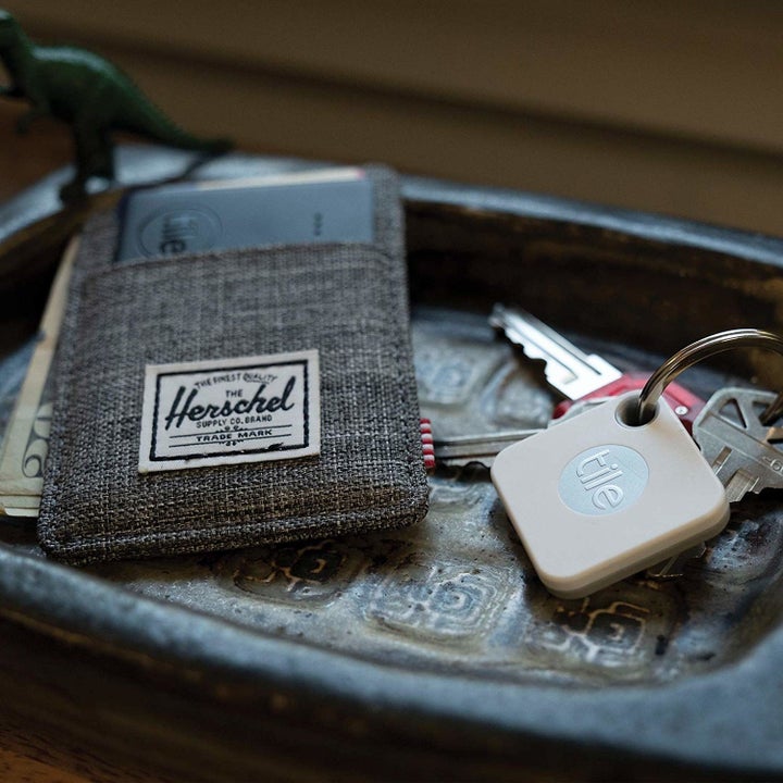 A wallet and a set of keys lie in a tray A rectangular card is sitting in a wallet slot