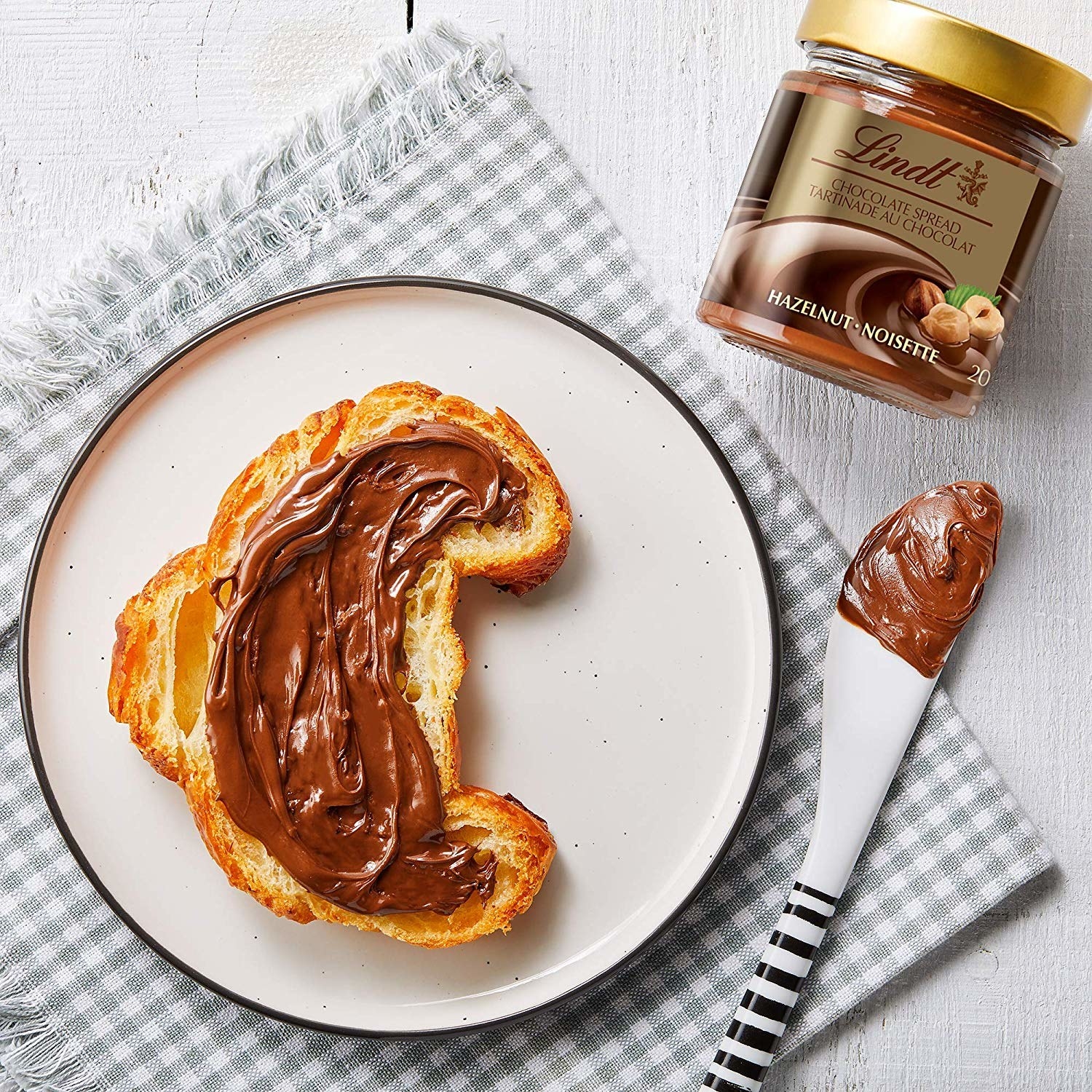 The jar of spread next to a croissant