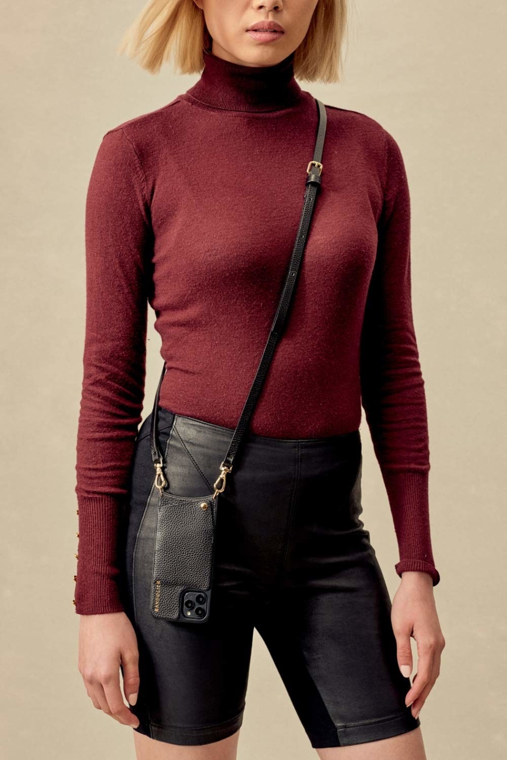 model with the black leather strap across their chest with the phone case with a pocket on the back