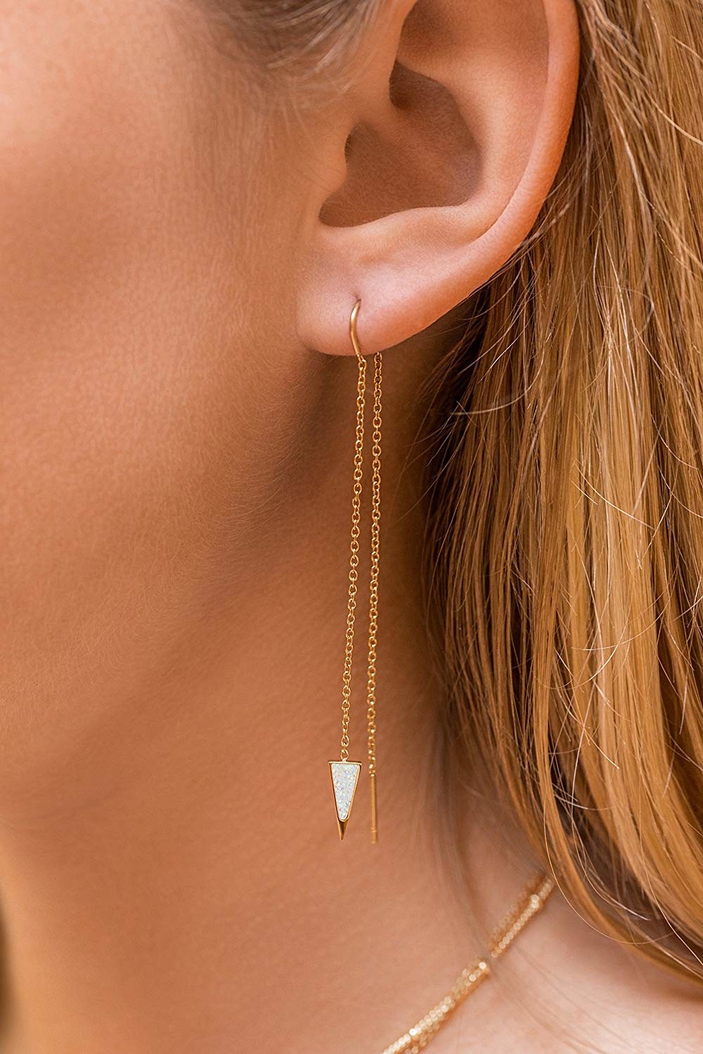 a model wearing chain drop earrings with a triangle on the end
