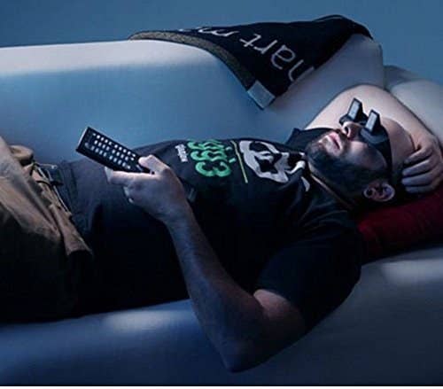 A Man lying on a couch wearing the lazy glasses and watching TV