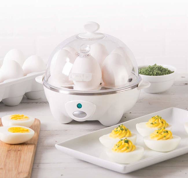 A transparent domed egg cooker with six eggs cooking inside