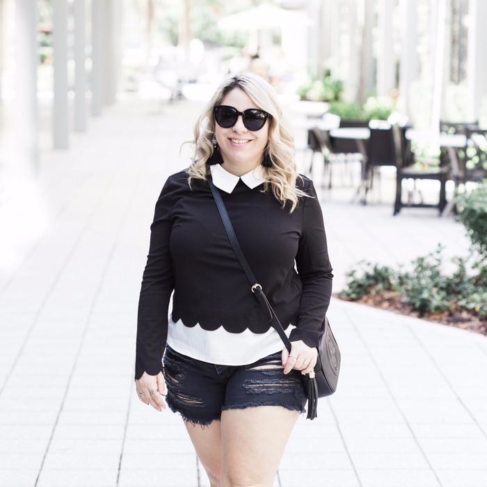 reviewer wearing the black and white collared sweater with a scallop hem