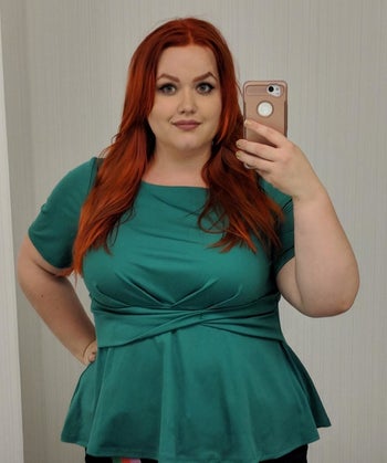 reviewer wearing the peplum top in green 