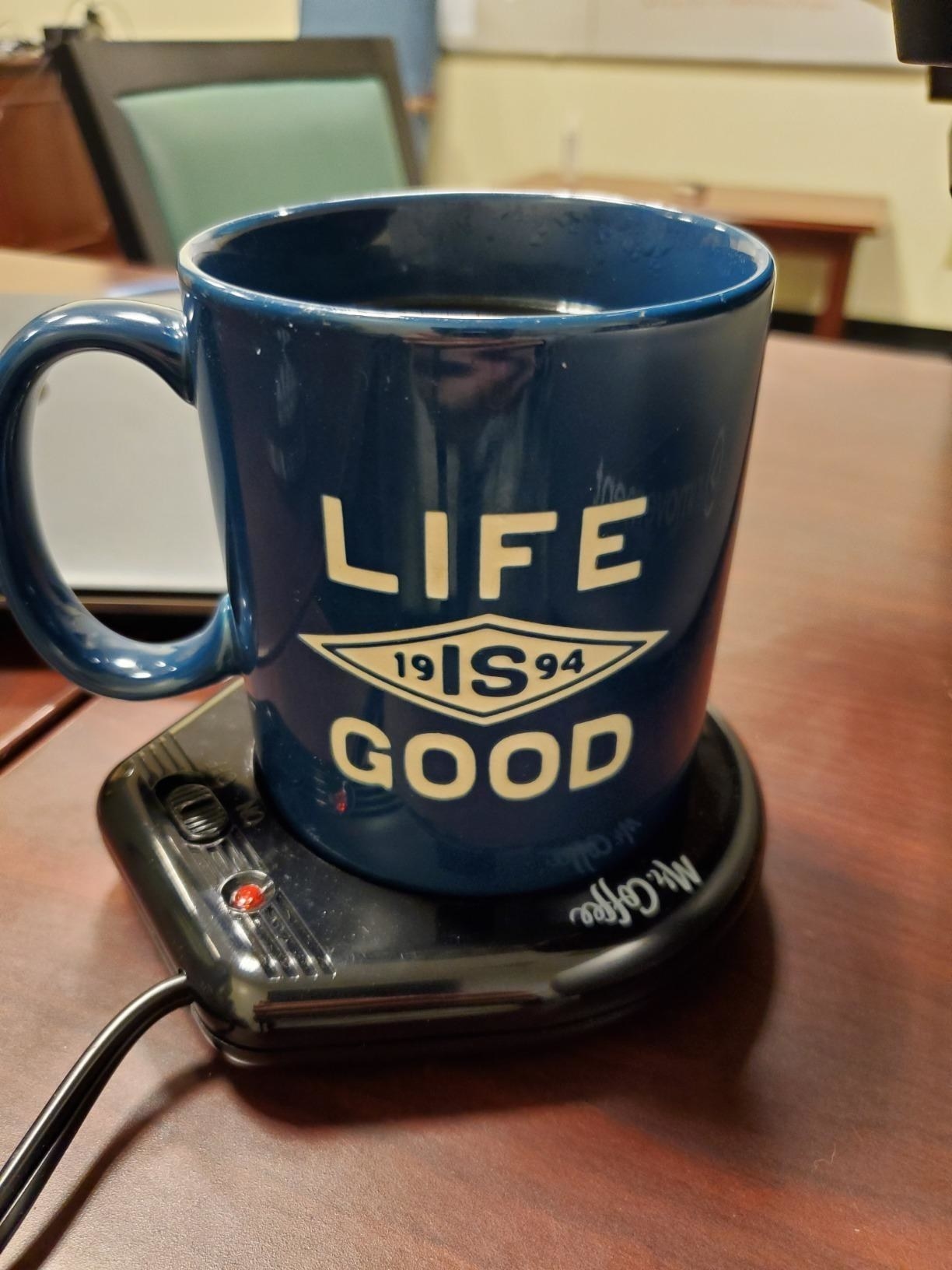 A mug of coffee on top of the black mug warmer pad 