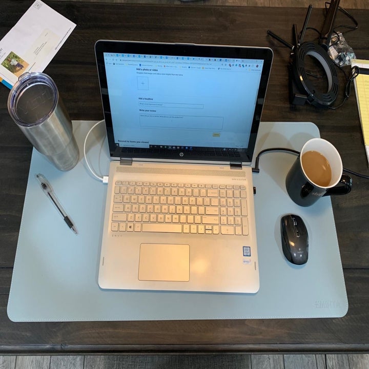Reviewer pic of the rectangle desk mat in blue with laptop, coffee, mouse and pen on it 