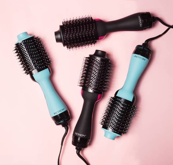 Four large electronic hair brushes lying on a plain background