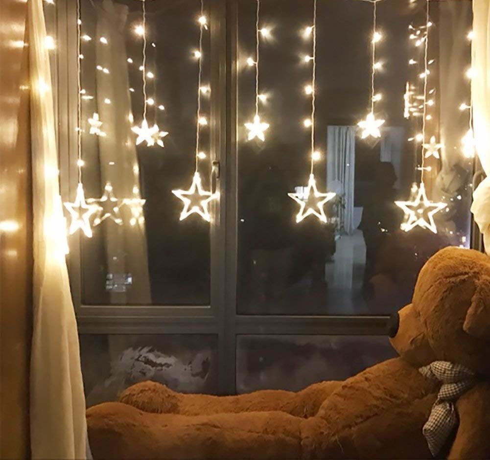 A teddy bear relaxing under fairy lights.