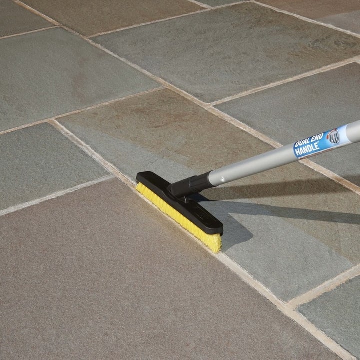 The grout brush attached to a broom handle