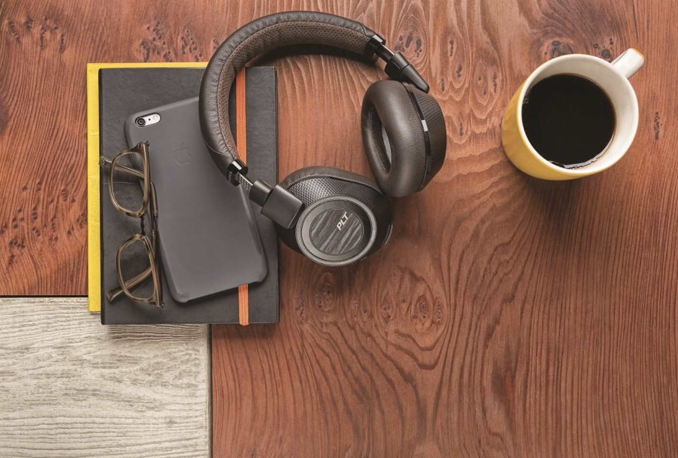 sleek black headphones on wooden table next to bullet journal and coffee