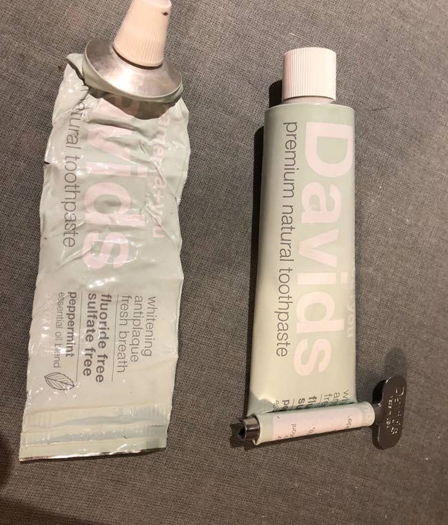 a reviewer photo of a wrinkled toothpaste tube and a full toothpaste tube with a key on the end to rollout left-behind product 