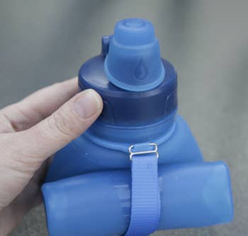 hand holds top of rolled-up collapsible water bottle