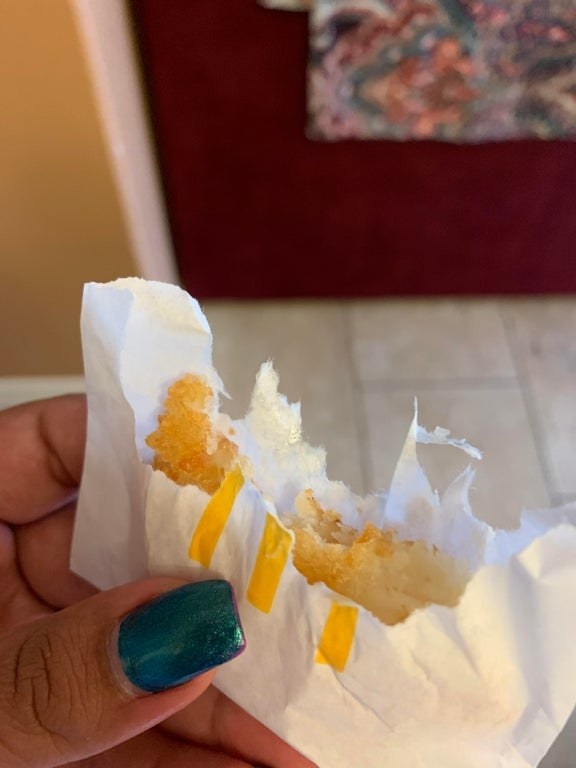 Picture of a McDonald&#x27;s hash brown that has been bit into, paper and all