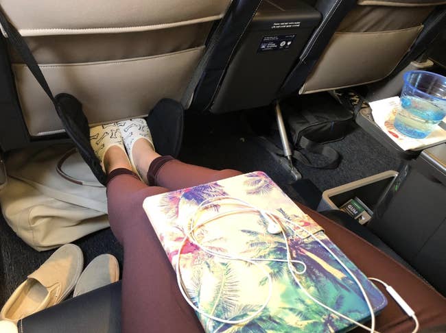 reviewer props up feet on black foot hammock behind plane seat