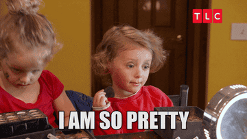 kid playing with a makeup brush in the mirror while saying &quot;I am so pretty&quot;