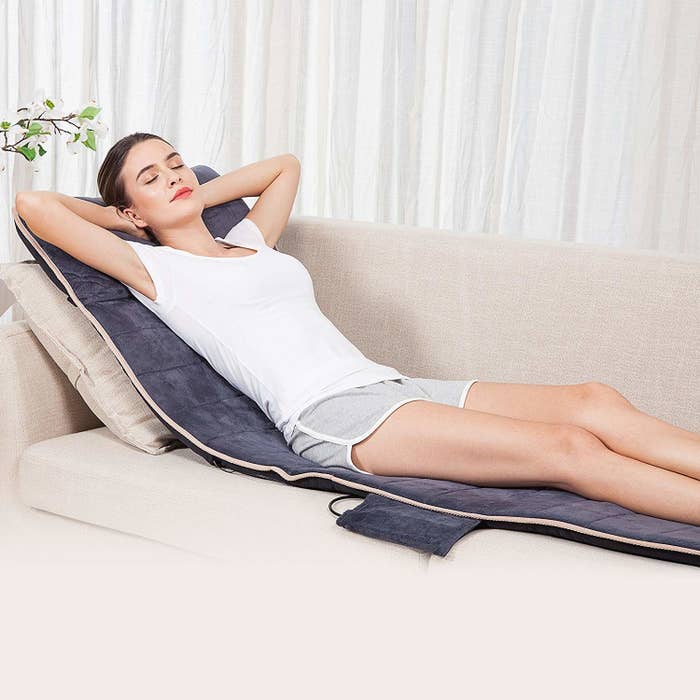 A person lying on the massage mat on their couch
