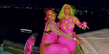 Nicki Minaj and Meg Thee Stallion hugging while wearing very bright pink outfits