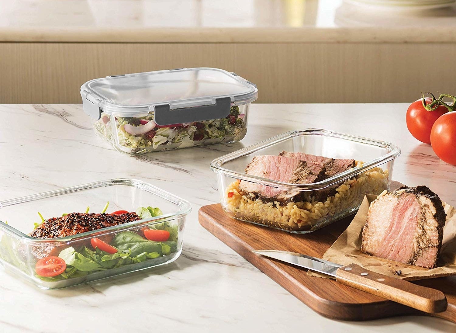 a salad, meat and rice, and salmon inside meal prep containers