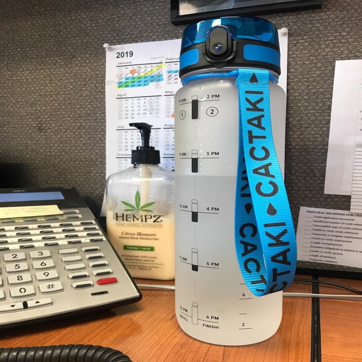 A transparent water bottle with markings on the side to show you how much water you've had, and a latch spout with a lid 