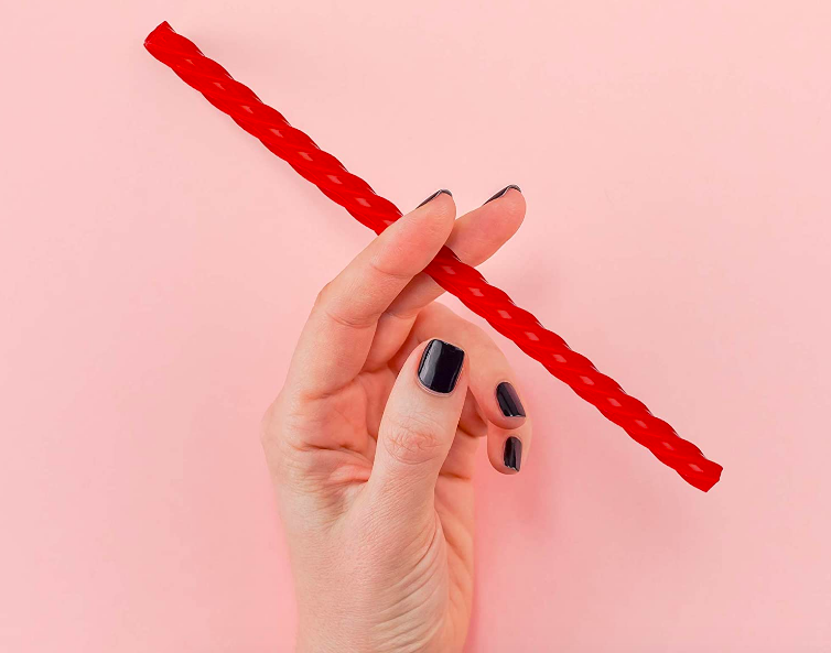 hand holding up a straw that looks like a long piece of licorice 
