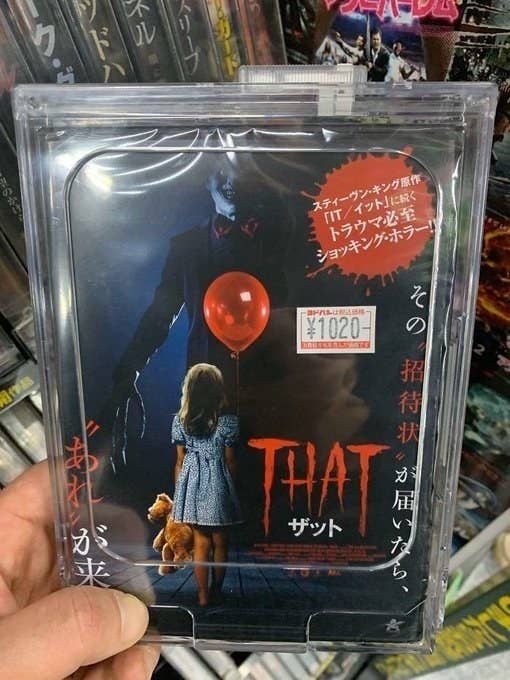 A person holds a DVD case for the movie quotThatquot which features a girl holding a teddy bear and red balloon with a sinister figure in the background