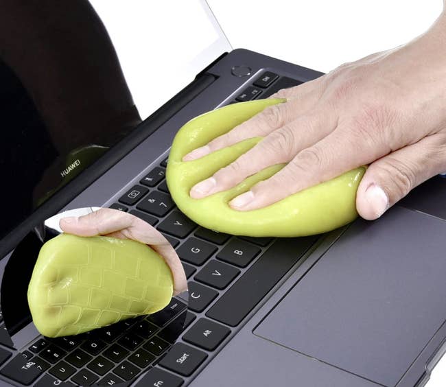 Model using a yellow squeegee to pull crumbs up from a mac keyboard 