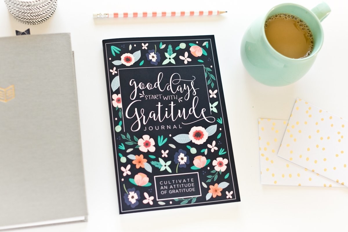 The navy floral cover of the journal with text that reads goods days start with gratitude 