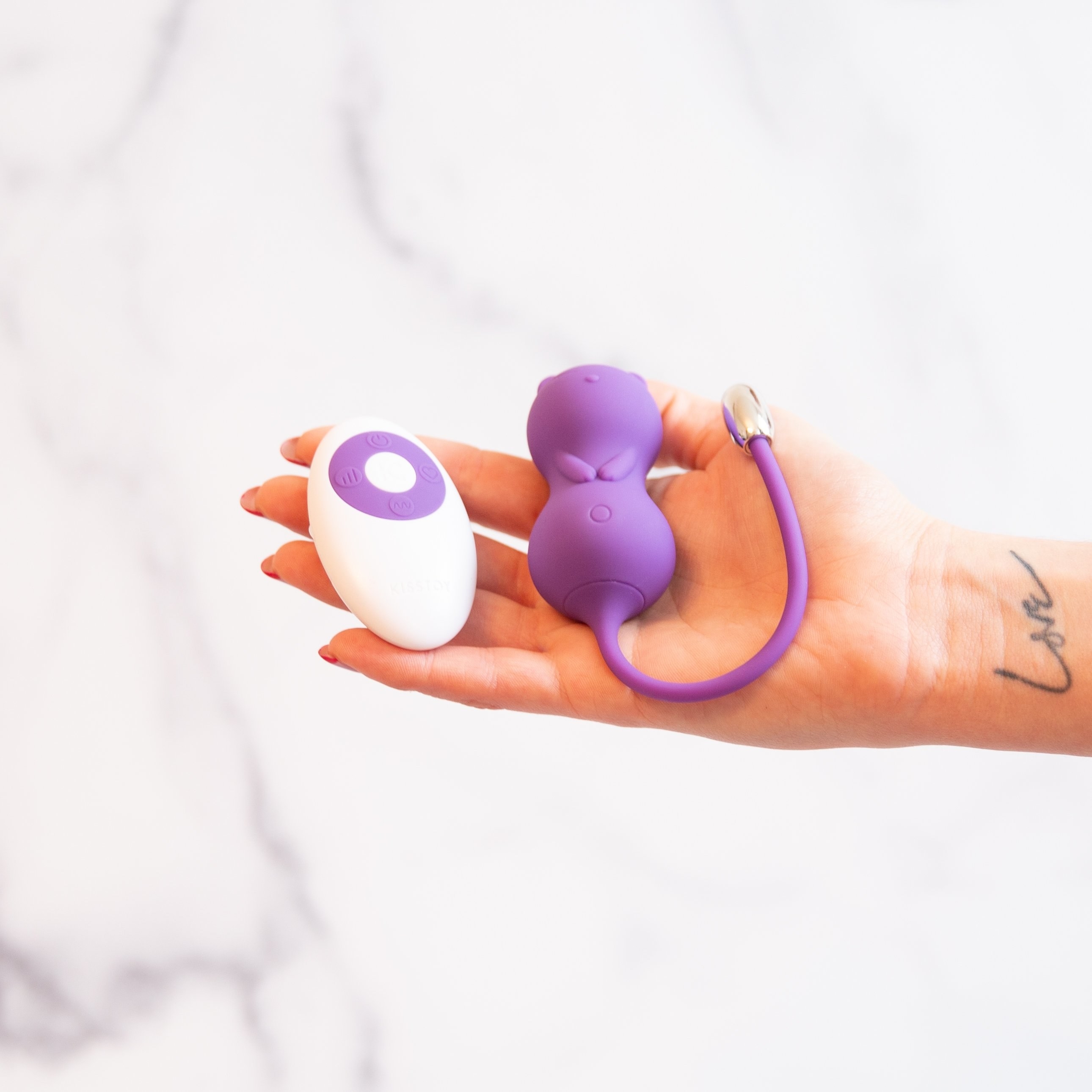 a hand holding the cat-shaped silicone vibe and remote 