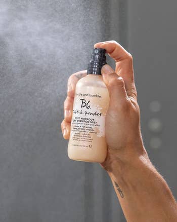 A hand spraying the dry shampoo mist 
