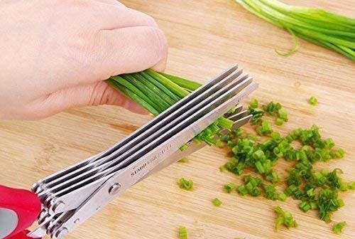 A hand cutting veggies with the scissors.