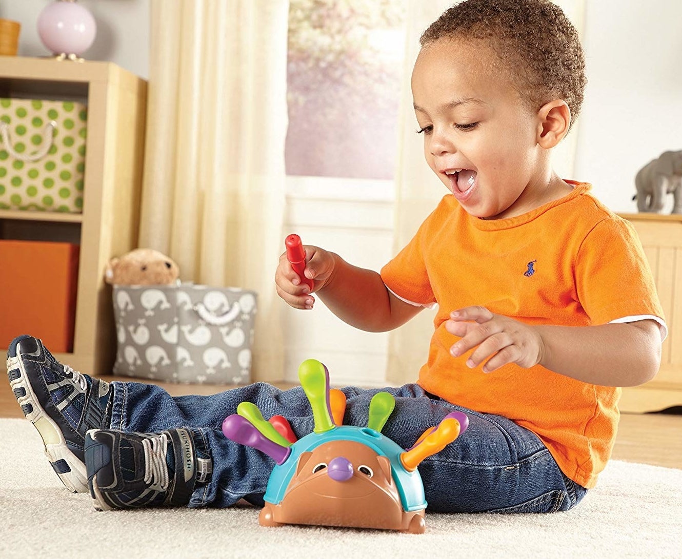 Child model playing with colorful plastic hedgehog toy