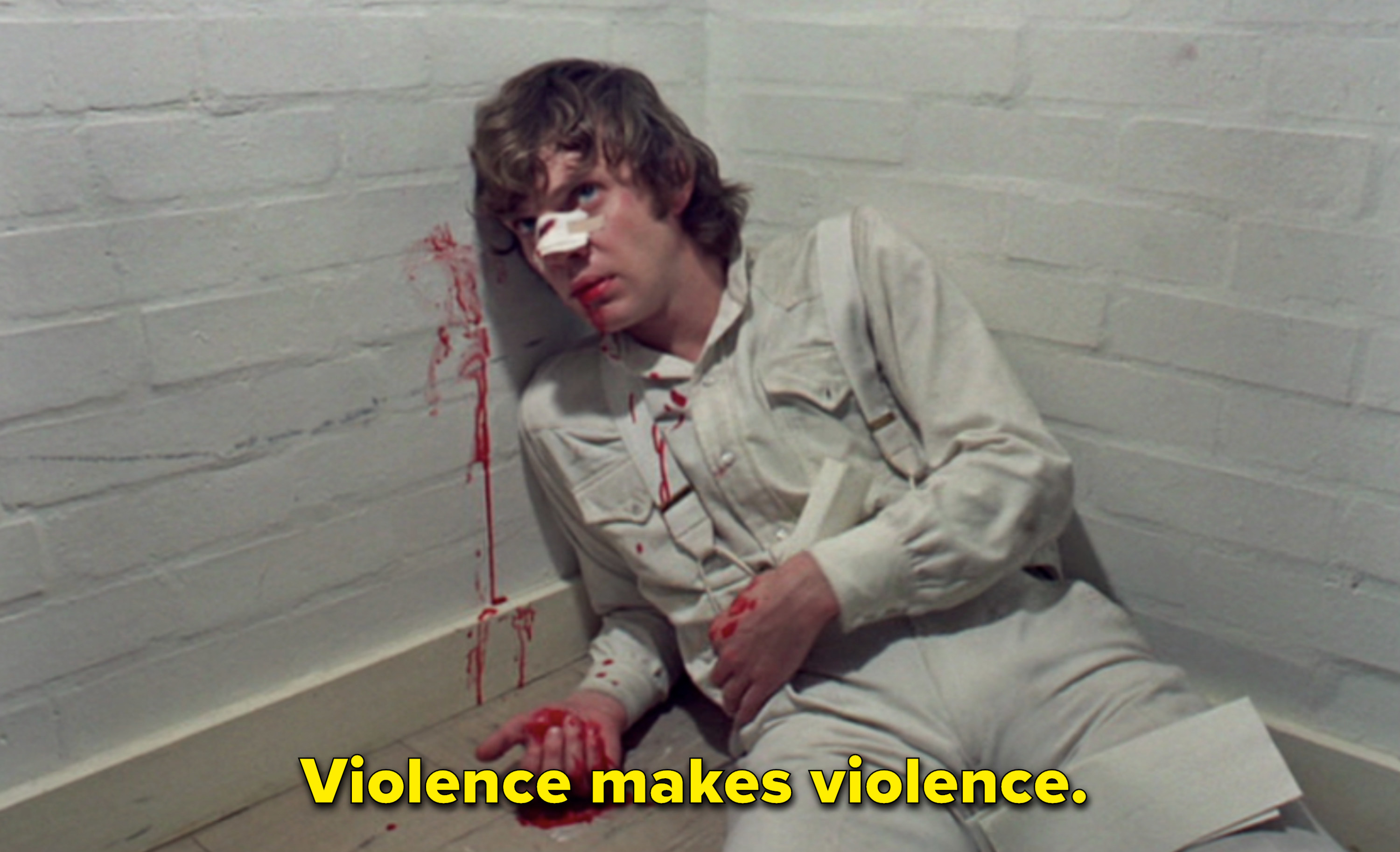 A bloodied Malcolm McDowell in a white jumpsuit