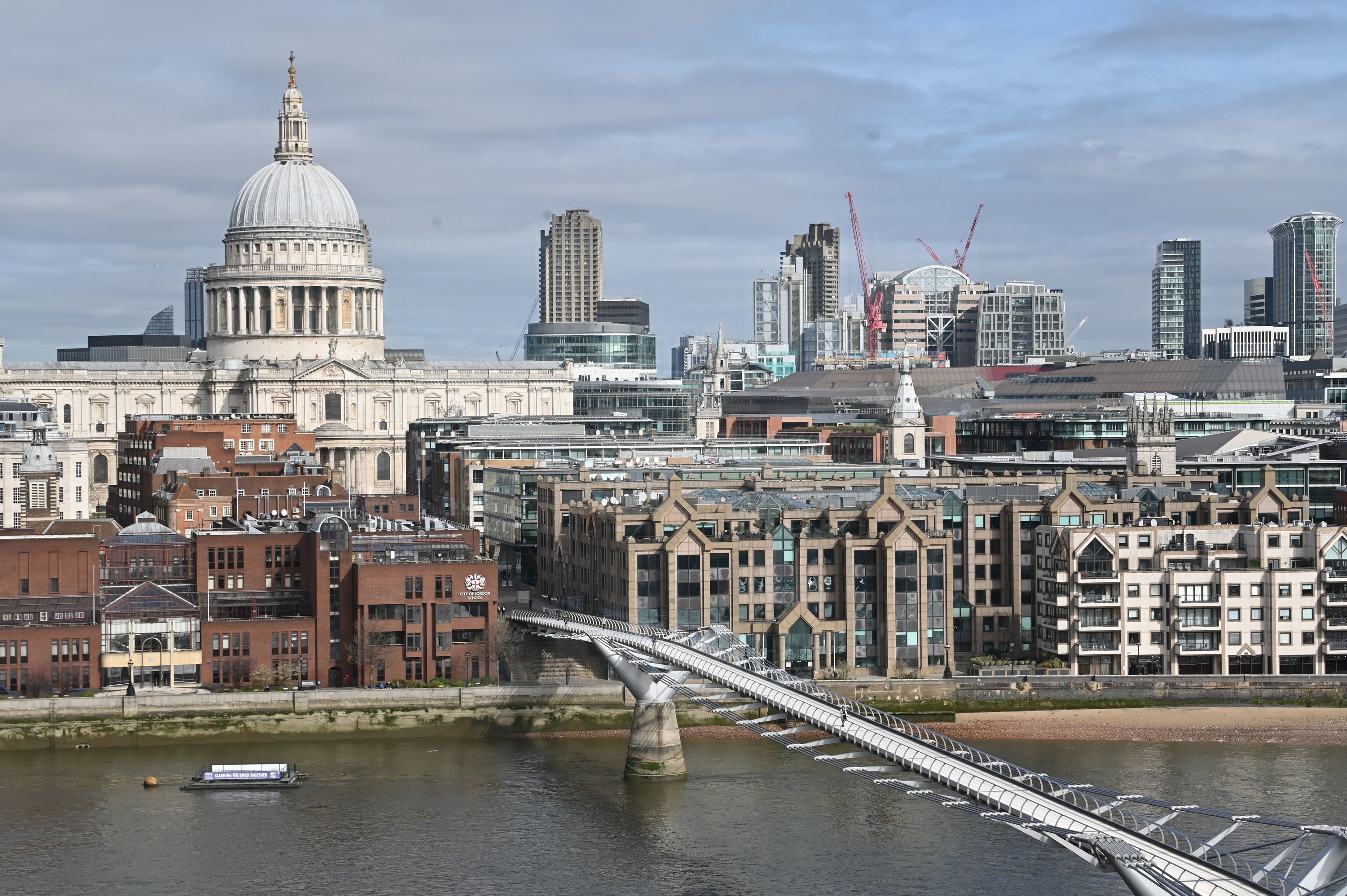 Pedestrians cross a quiet Millennium Footbridge across the River Thames in London in the mid-morning on March 17, 2020.