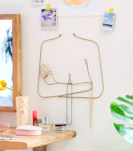 A female silhouette jewelry organizer with necklaces next to a dresser