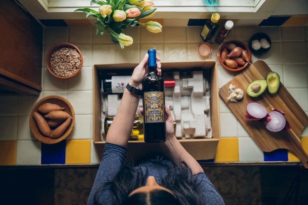 person holding a bottle of wine that came out of a box