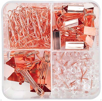 the rose gold paper clips, push pins, and binder clips in a clear container 