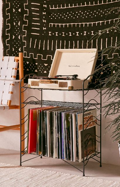 A black storage shelf with a record player on top and several vinyls on the bottom