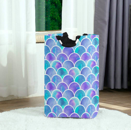 Purple and blue mermaid-pattern laundry basket on a white rug
