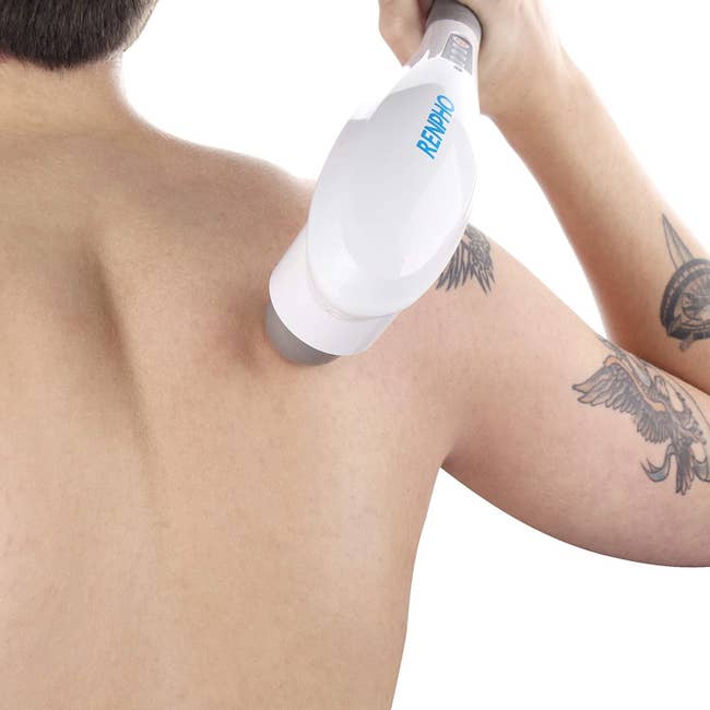 person not wearing a shirt using the large wand-like massager to reach a part of back their hand wouldn't 
