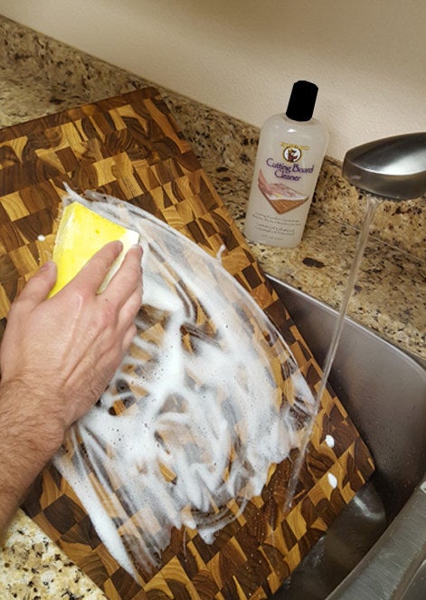 Reviewer cleaning cutting board with cleaner and sponge