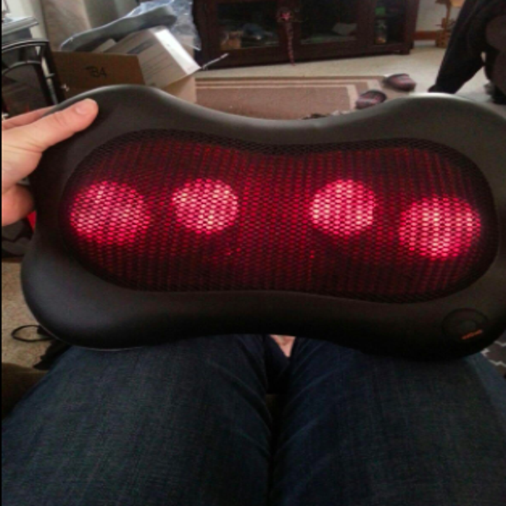 person holding the massager for scale and to see the heated nodules