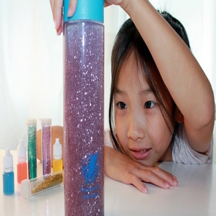 A child model playing with a sparkly tube from the box