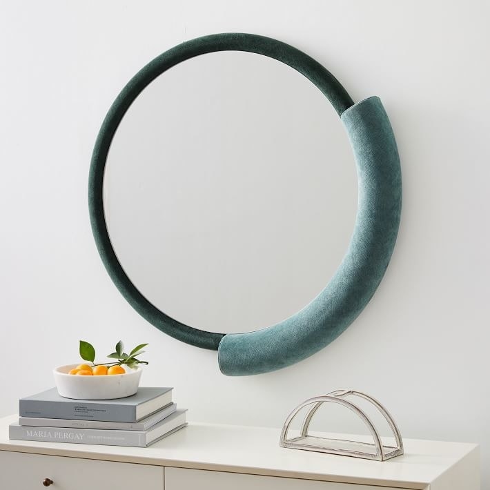 round mirror with what looks like half a pool noodle on one side 