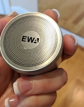Reviewer holding the round palm-size speaker