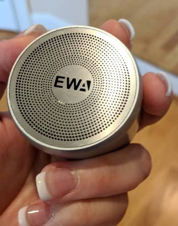 Reviewer holding the round palm-size speaker