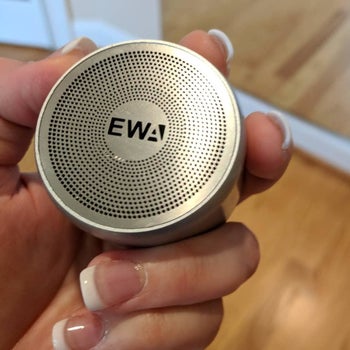 Reviewer holding the round palm-size speaker