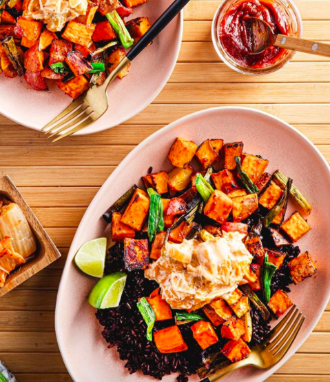 Two dinner plates full of sweet potatoes, cauliflower, and other various vegetables.