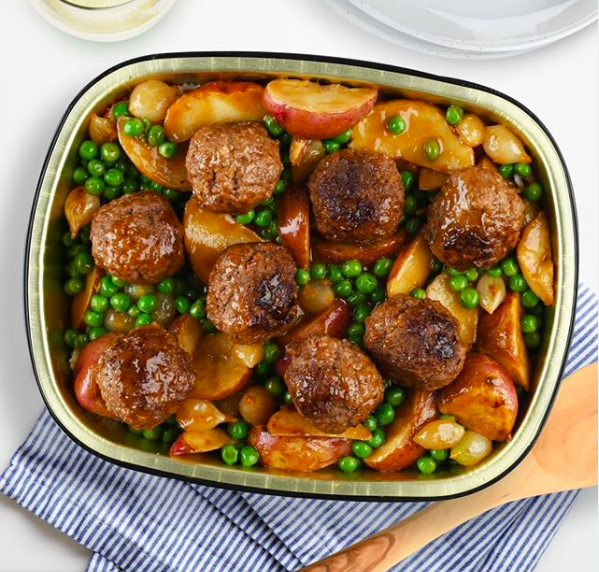 A bowl of meatballs, peas, and potatoes 